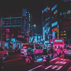 a city street filled with lots of traffic and tall buildings in the background at night