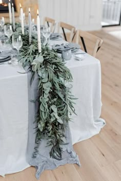 the table is set with candles and greenery