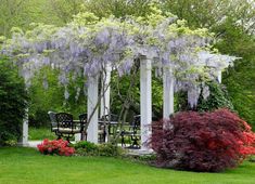 a gazebo in the middle of a garden with flowers growing on it and benches underneath