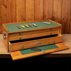 two wooden boxes with different types of knives in them sitting on a table next to a wood paneled wall