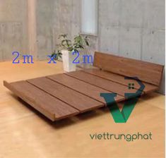 a wooden bed frame sitting on top of a hard wood floor next to a potted plant