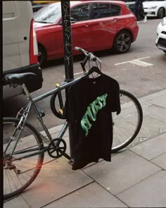 a bike parked next to a pole with a t - shirt hanging on it's side