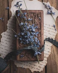 some blue flowers are sitting on a piece of paper next to an old fashioned book