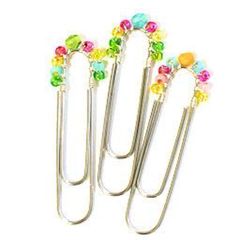 four metal binders with colorful beads on each one and a paper clip in the middle