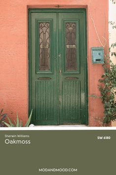 a green door is in front of a pink building