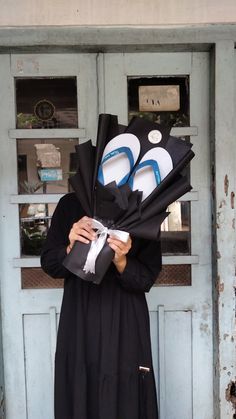 a woman in a black dress is holding two pairs of flip flops