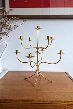 a gold candelabra with six candles on it sitting on a wooden table