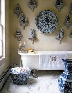 a white bath tub sitting under a window next to a wall with plates on it