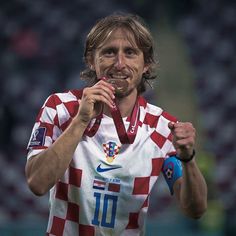 a man holding a medal in his right hand while wearing a red and white shirt