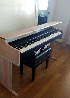 a piano sitting on top of a hard wood floor next to a wall with a window