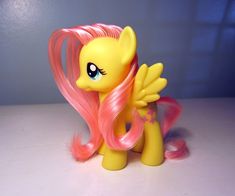 a yellow pony with pink hair sitting on top of a table