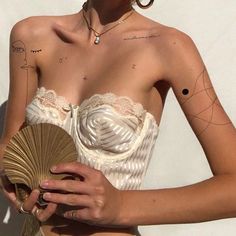 a woman with tattoos on her chest holding a fan