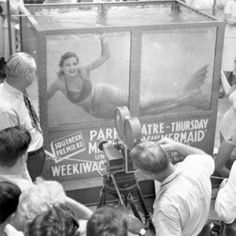 an old black and white photo of a woman dancing in front of a large poster