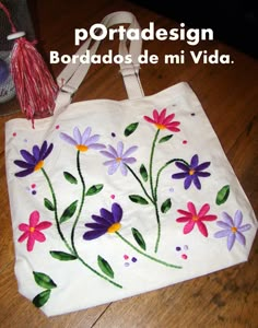 a bag with flowers painted on it sitting on top of a wooden floor next to a tassel