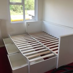 an empty bed frame in a room with red carpeted flooring and white walls