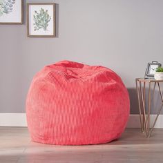 a large pink bean bag sitting on top of a wooden floor next to a table