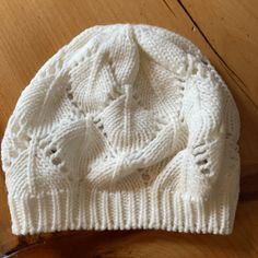 a white knitted hat sitting on top of a wooden table