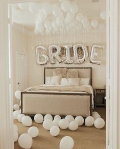 balloons are floating in the air over a bed with a bride sign above it and white balls on the floor