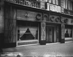 an old black and white photo of a storefront with the word chocolate on it