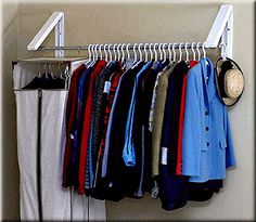 a rack with clothes hanging on it next to a wall mounted mirror and coat rack