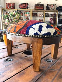 a wooden bench with a multicolored cushion on it's legs and feet