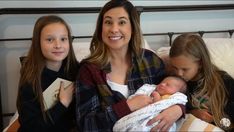 a woman and two girls are holding a baby