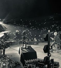 a black and white photo of a band performing on stage with lights in the background