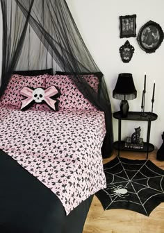 a bed with pink and black sheets in a bedroom next to a spider web rug