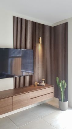 a living room with a large television mounted on the wall next to a potted plant