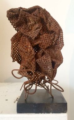 a sculpture made out of wire and fabric sitting on top of a white table next to a wall