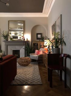 a living room filled with furniture and a fire place under a mirror on the wall