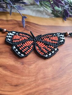 an orange and black beaded butterfly on a wooden table