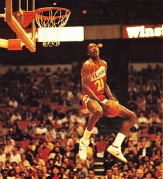 a basketball player jumping up to dunk the ball in front of an arena full of people