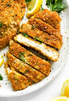 chicken cutlets on a plate with lemon wedges and parsley sprigs