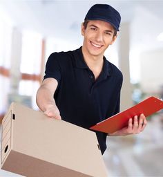 a young man is holding a box and pointing at the camera with his right hand