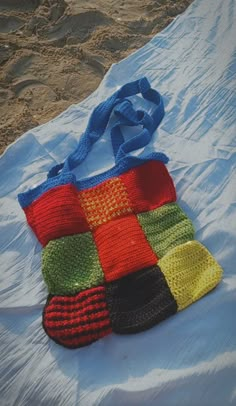 a crocheted bag sitting on top of a bed covered in white sheeting