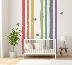 a baby's room with a crib and wall decals in rainbow colors