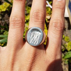 a woman's hand with a ring on it that has two horses in the middle