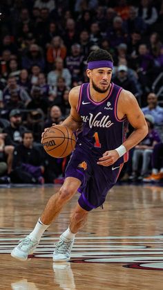 a basketball player dribbling the ball during a game with an audience in the background