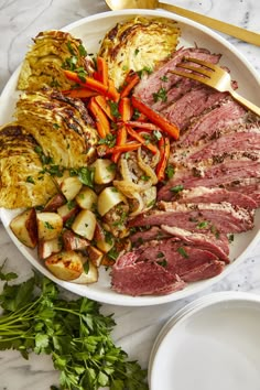 a white plate topped with corned beef, potatoes and carrots next to a fork