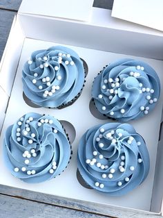 three cupcakes in a box with blue frosting