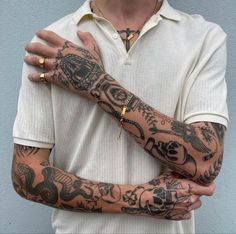 a man with tattoos on his arm and wrist holding onto another person's arm