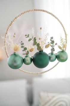 three green ornaments hanging from the ceiling in front of a white couch with pillows on it