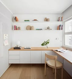 a desk and chair in a room with shelves on the wall above it, next to a window