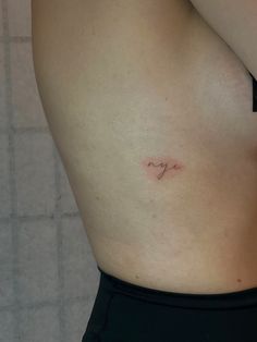 a woman's stomach with a small tattoo on her left side and the word love written in cursive writing