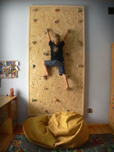 a young boy climbing up the side of a wall with a yellow bean bag chair