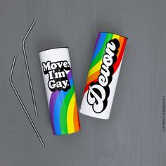 two coffee cups with the words move i'm gay on them next to a pair of straws