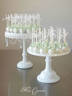 two white cake stands with green and white candies on them