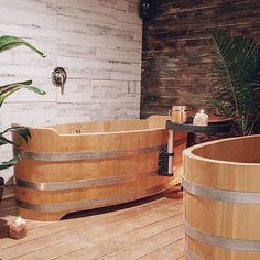 a large wooden tub sitting on top of a wooden floor next to a potted plant