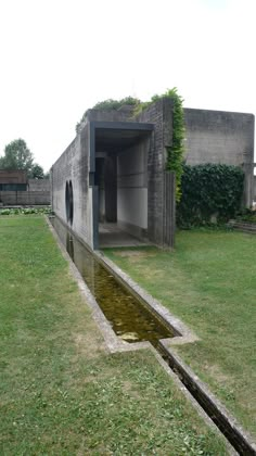 an open door on the side of a building next to a small pool of water